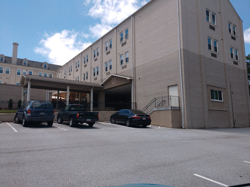 A view of a multi-story building with a parking lot in front, set against a partly cloudy sky.