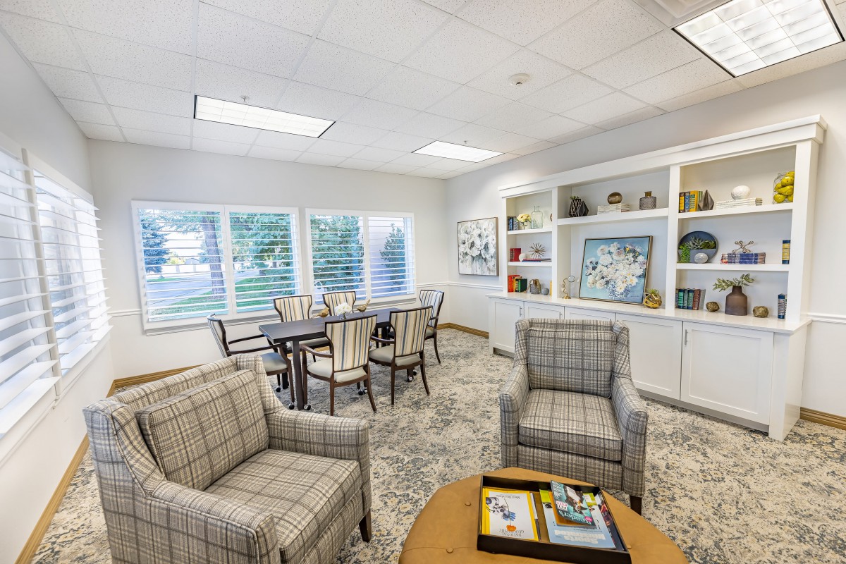 A cozy indoor seating area with plaid chairs, a round table, and decorative shelves.