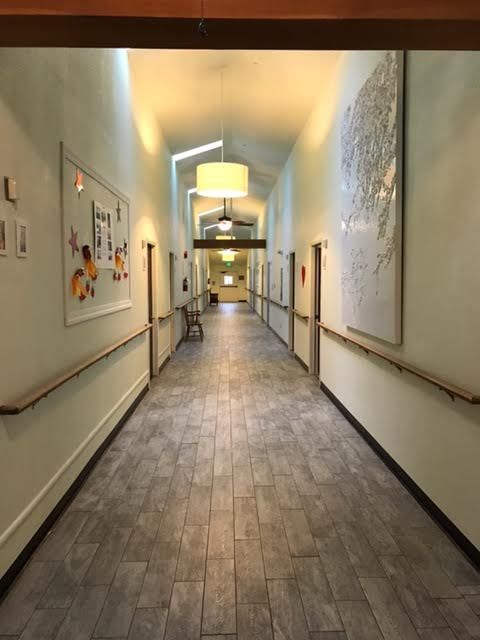 A well-lit hallway with artwork on the walls and a tiled floor.