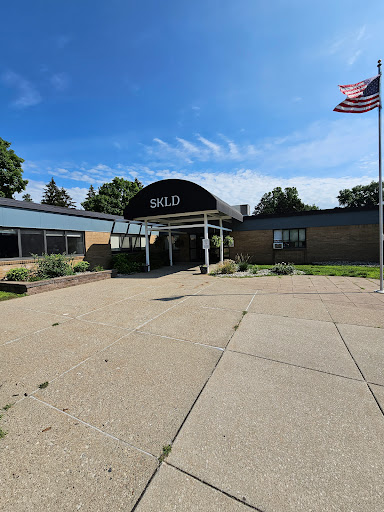 A sunny day at the entrance of a building with an American flag.
