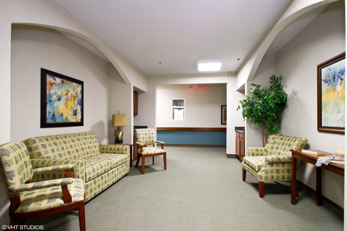 A cozy waiting room with sofas, artwork, and a potted plant.