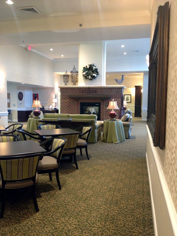 A cozy lounge area with comfortable seating, tables, and a central fireplace.