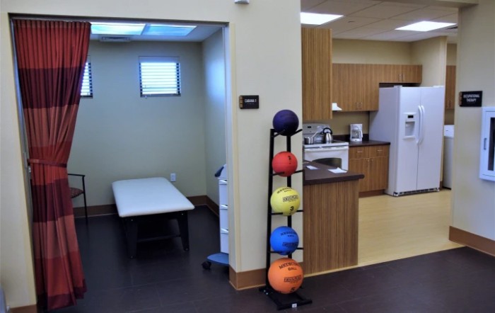 A therapy room within a clinic featuring exercise equipment and a treatment bed.