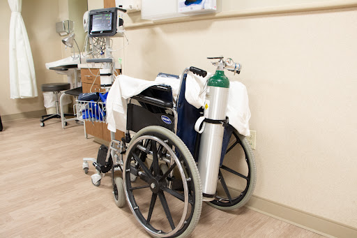 A wheelchair with an attached oxygen tank in a healthcare setting.