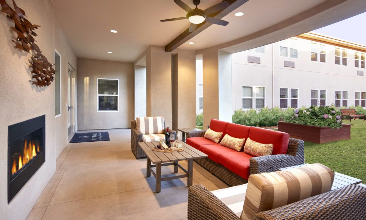 A modern outdoor patio with comfortable seating and a ceiling fan.