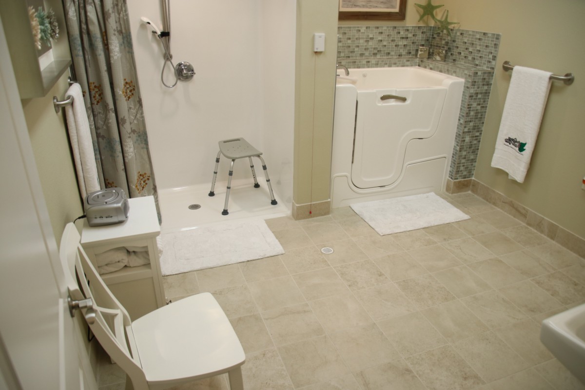 An accessible bathroom featuring a walk-in tub and a shower area equipped with a safety chair and non-slip mats.