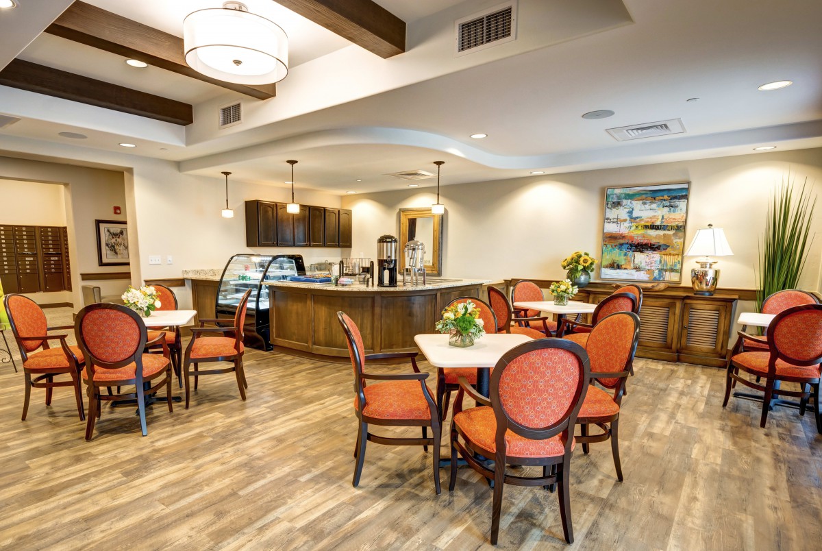 A cozy cafe interior with tables, chairs, and warm lighting.