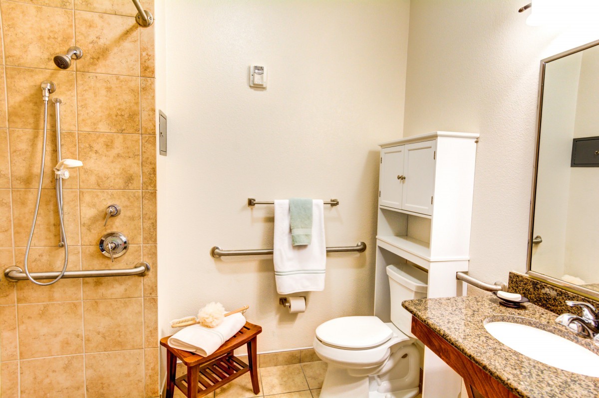 A clean and organized bathroom featuring a toilet, shower, and towels.