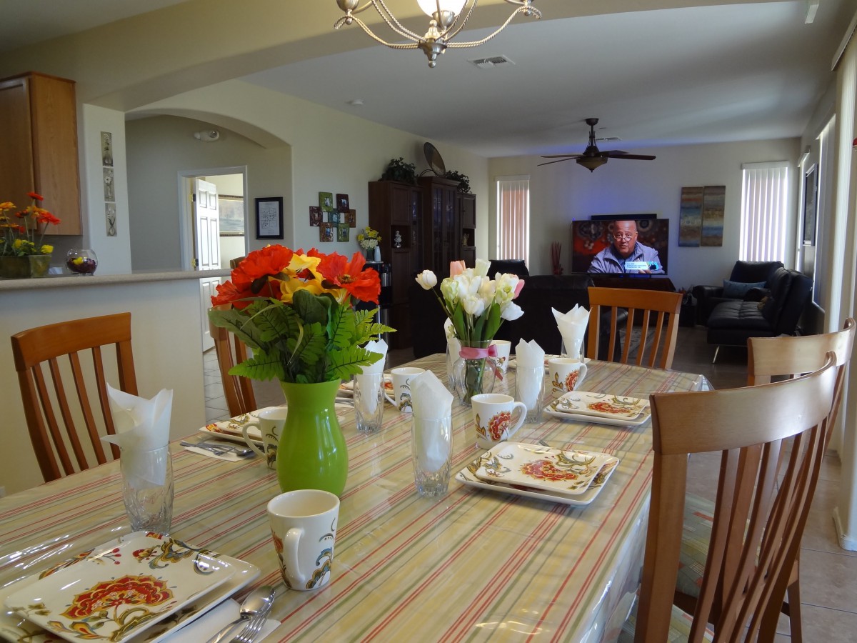 A well-set dining table with colorful flowers and neatly arranged dinnerware in a cozy home interior.
