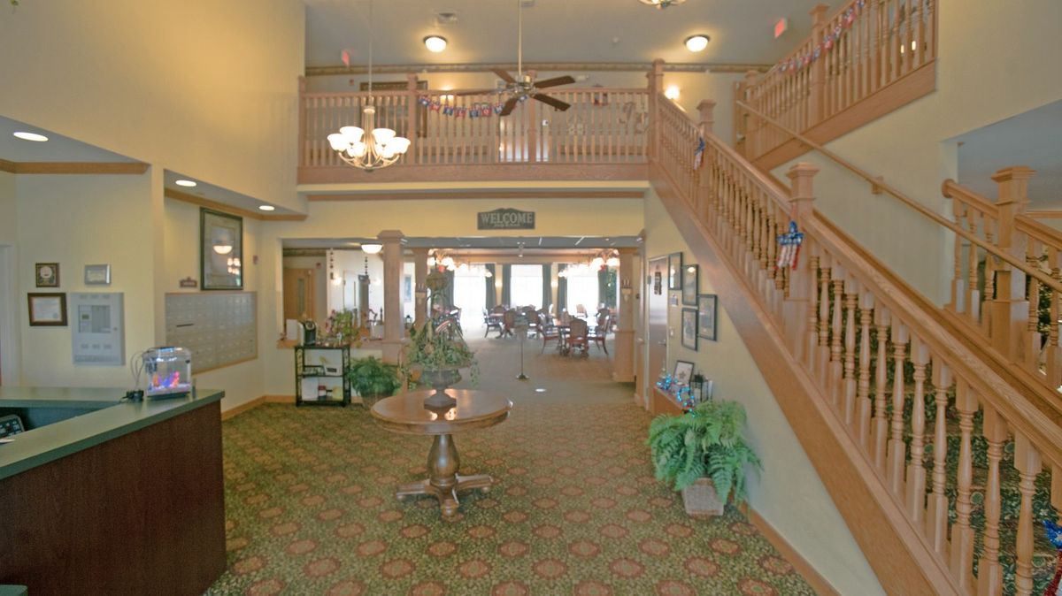 A spacious and elegant lobby featuring a grand staircase, chandelier, and comfortable seating.