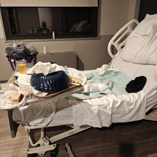 A hospital room showing a cluttered patient bed with leftover food and trash.