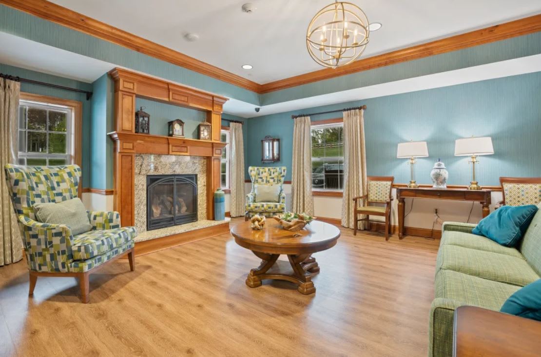 A cozy living room with blue walls, featuring a fireplace, wood flooring, and comfortable seating.