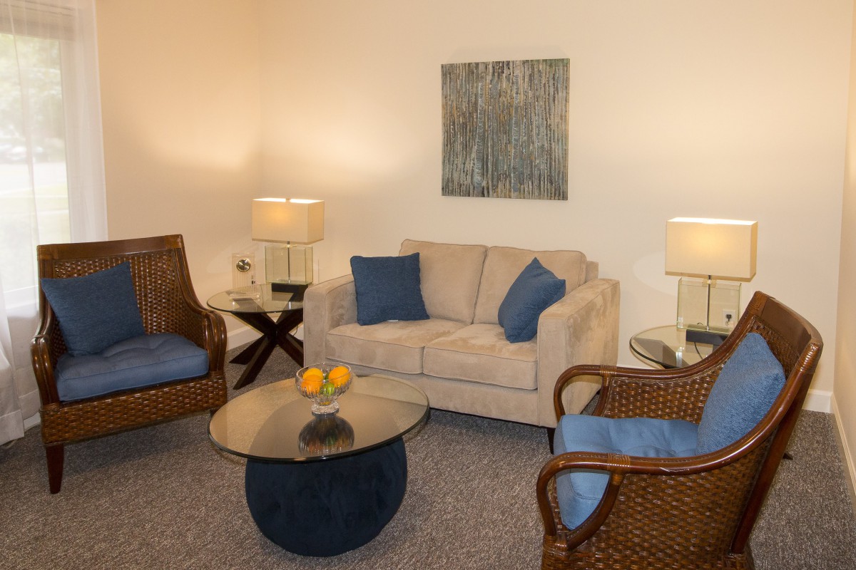 A cozy living room with a beige sofa, matching wicker chairs, and a round coffee table.