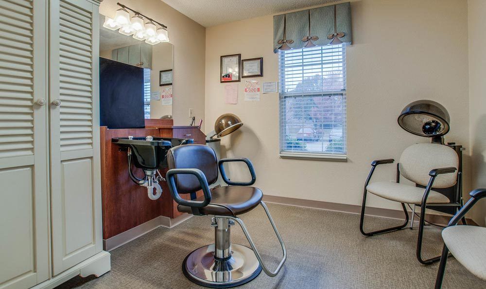 A cozy salon space with a barber chair, mirror, and hair dryer beside a window.