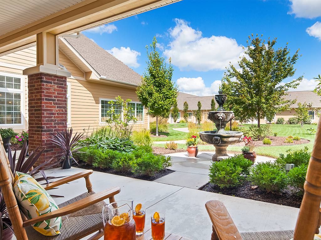 A sunny patio with seating and a picturesque garden featuring a fountain.