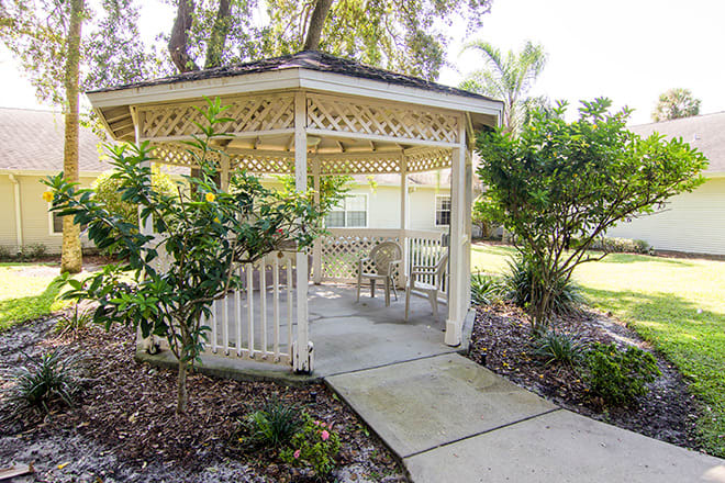 A charming garden gazebo with patio furniture and surrounding greenery.