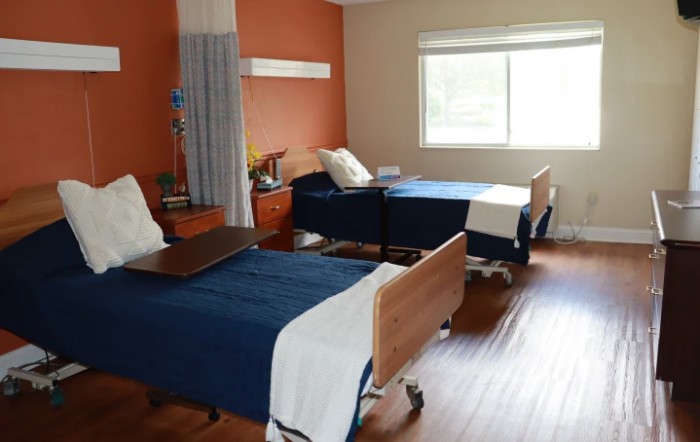 A clean and organized hospital room with two beds and medical equipment.