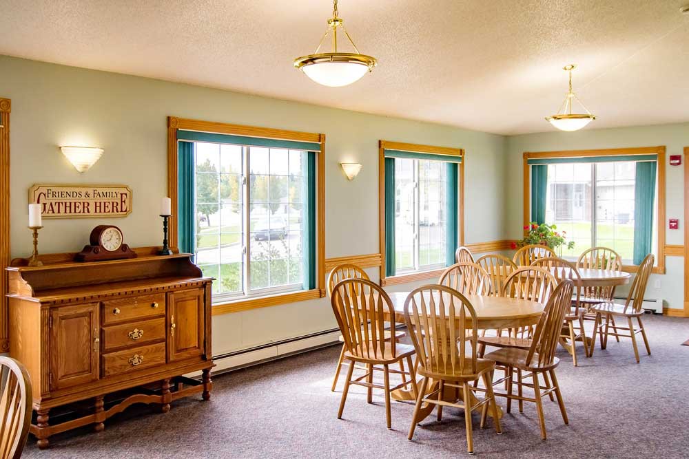 A bright dining room with wooden furniture and large windows.