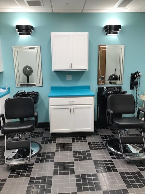 A neatly arranged barbershop interior featuring styling chairs and mirrors.