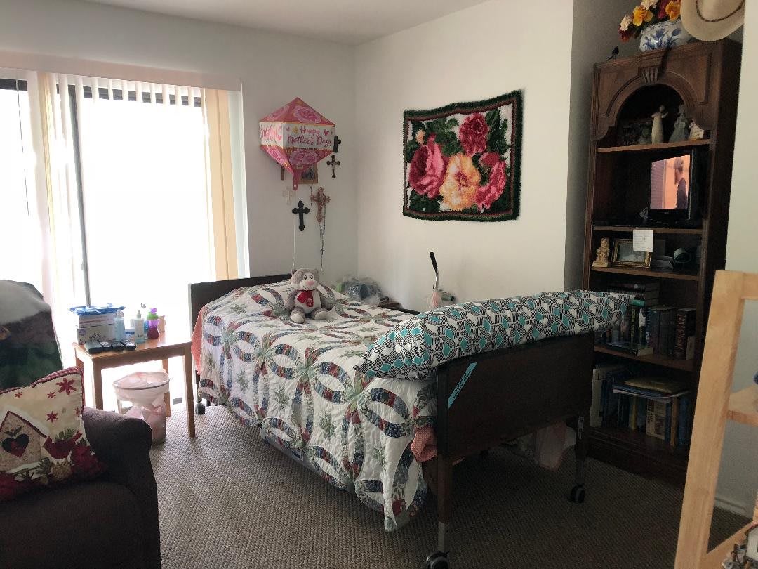 A bedroom with a hospital bed, decorated with floral patterns and a pink balloon.