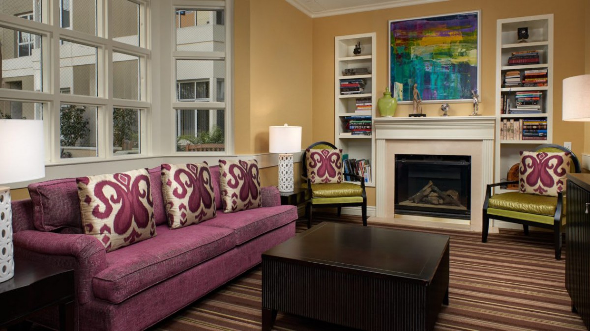 A cozy living room featuring a colorful sofa, decorative pillows, and a modern fireplace.
