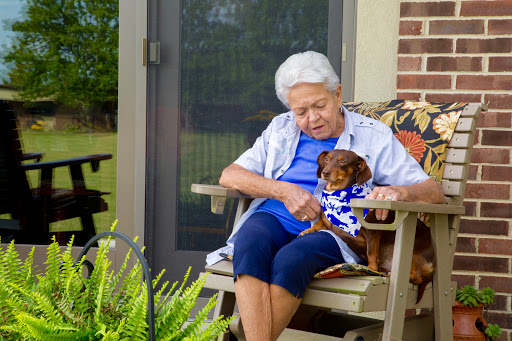 An elderly woman enjoying a peaceful moment on her porch with her dog.