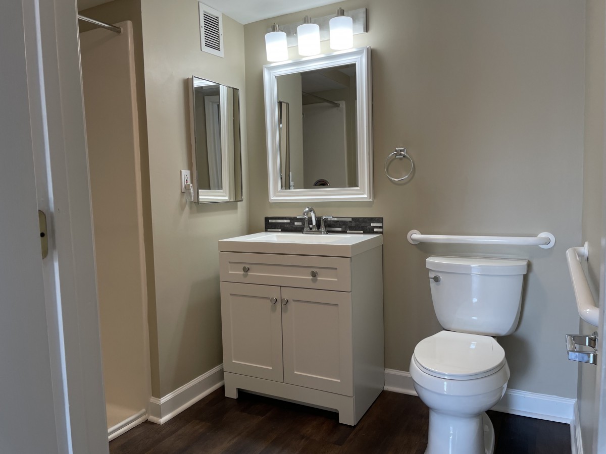 A modern bathroom with a vanity, mirror, and toilet.