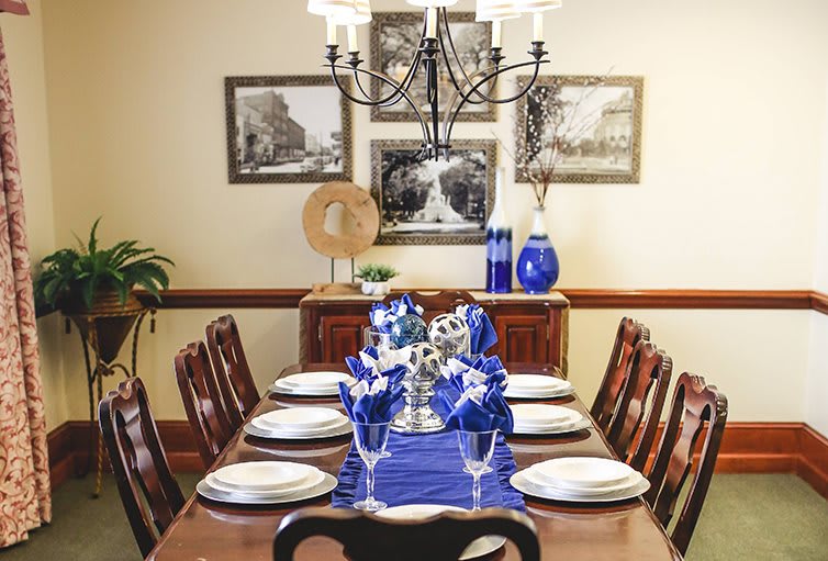 A beautifully arranged dining table with blue accents and elegant decor under a classic chandelier.