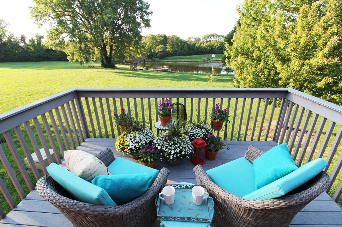 A cozy patio with wicker chairs and colorful cushions overlooking a lush garden.