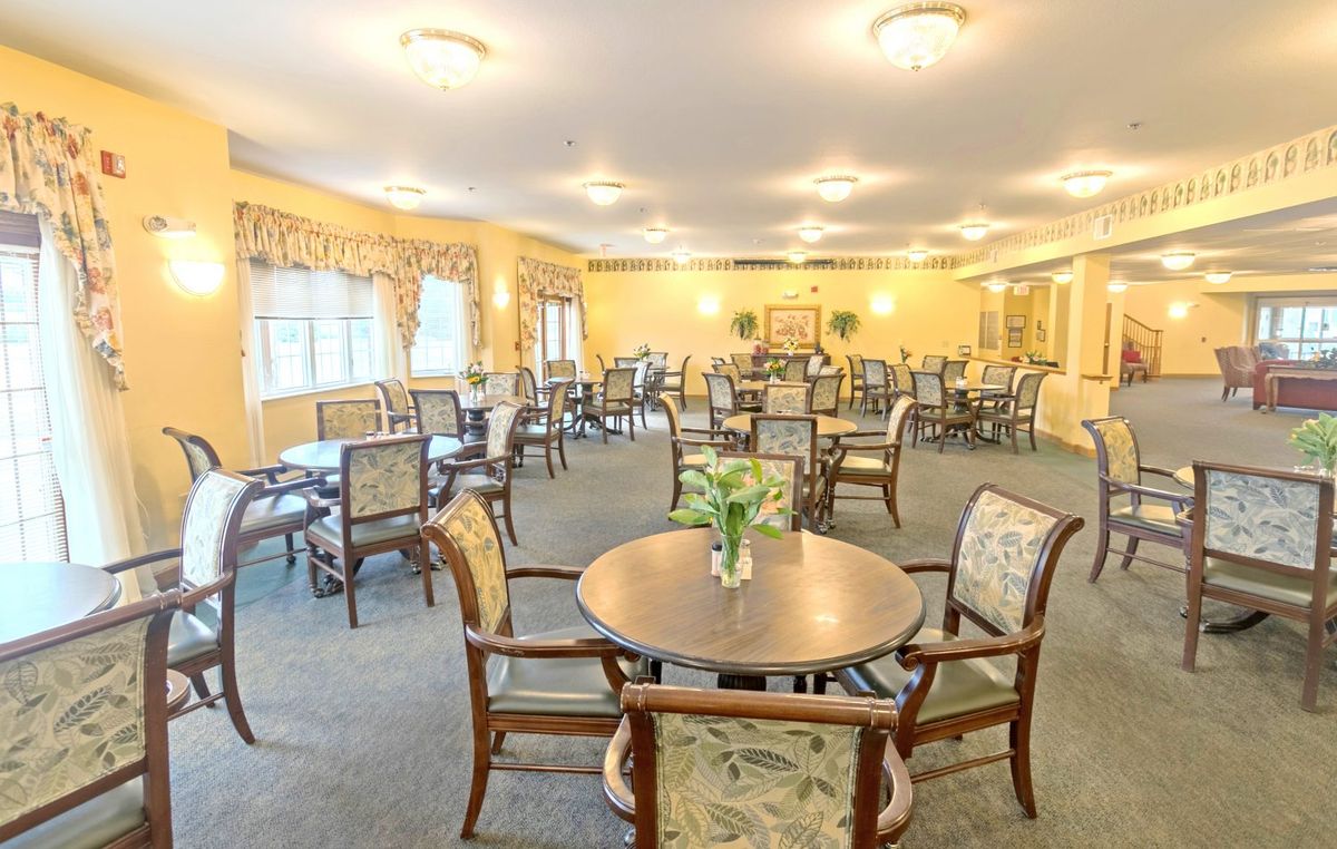 A well-lit dining room with multiple tables and chairs, decorated in warm tones.