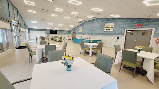 A spacious and modern dining area set up for an event, featuring neatly arranged tables and chairs.