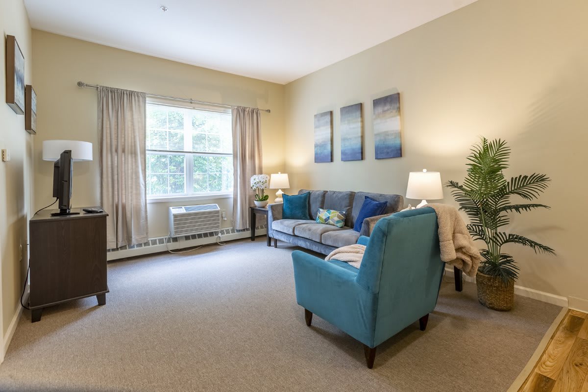 A cozy living room with a blue sofa, armchair, and decorative artworks.
