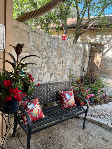 A cozy outdoor seating area adorned with vibrant flowers and decorative pillows, perfect for relaxation.
