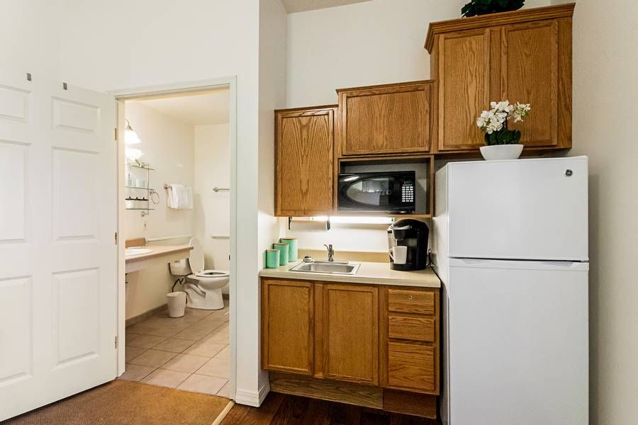Compact apartment kitchen with wooden cabinets and adjacent bathroom.