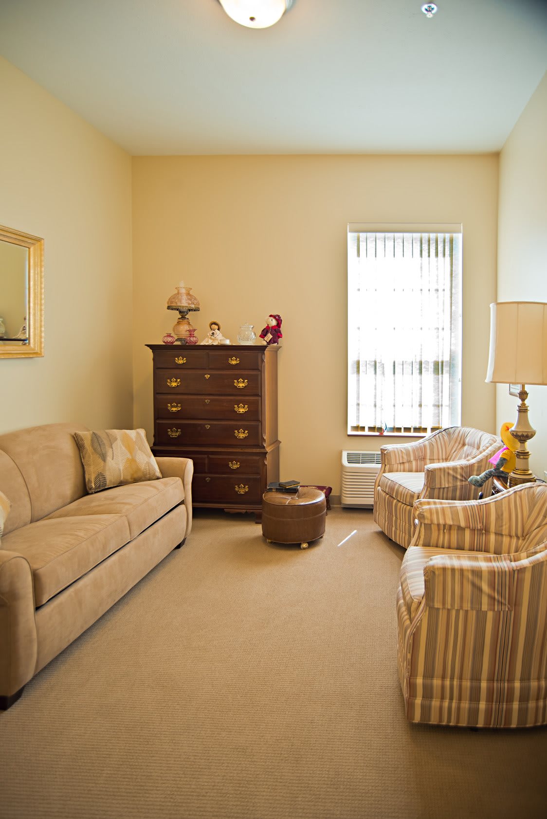 A cozy living room with a sofa, armchairs, and a cabinet.