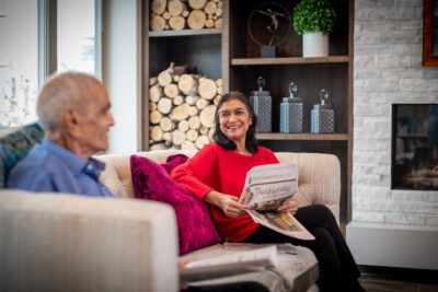 A couple relaxing in a cozy living room, with one person reading a newspaper.