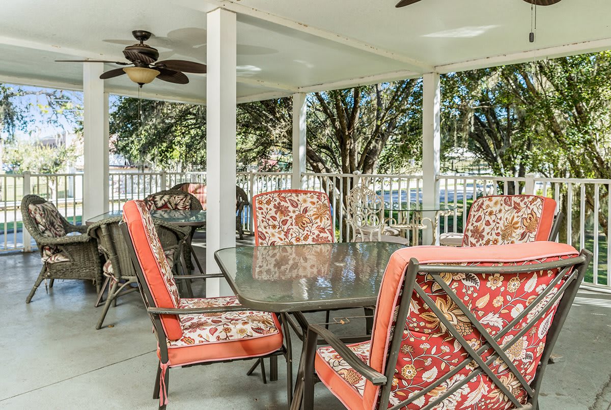 A cozy outdoor patio with a glass table and chairs under a covered area.