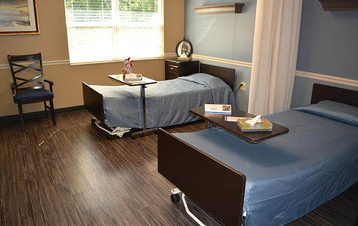 A well-lit hospital patient room featuring two beds with side tables.