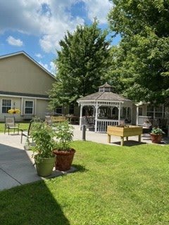 A peaceful outdoor area featuring a gazebo, surrounded by greenery and a well-kept garden.