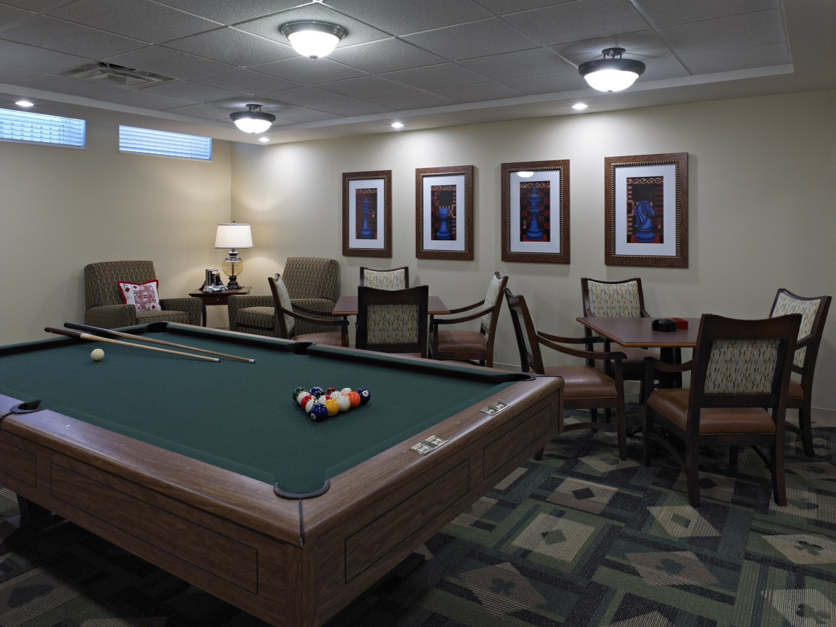 A cozy game room featuring a pool table, comfortable seating, and framed artwork on the walls.