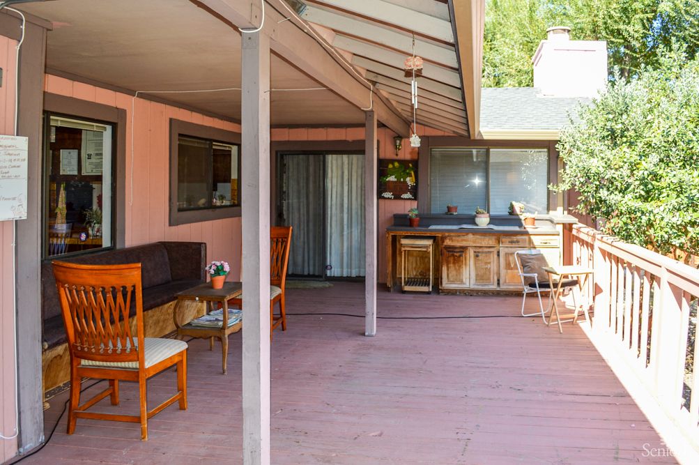 A cozy outdoor patio with furniture under a covered area.