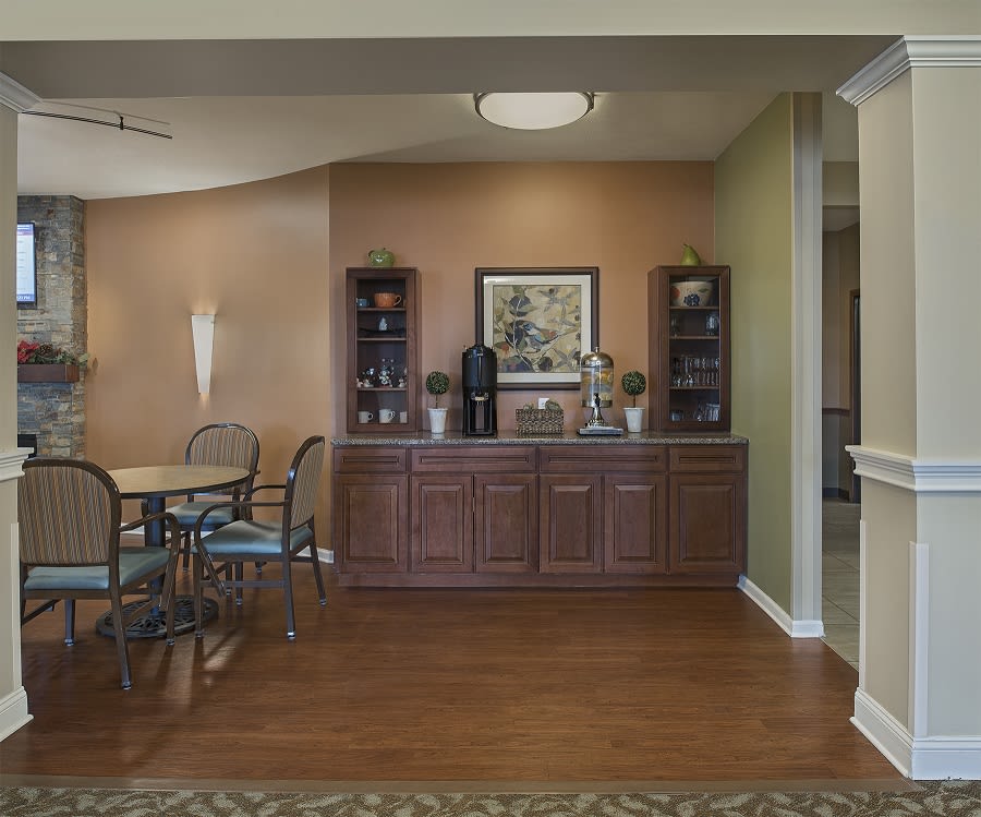 A cozy dining area with a table and chairs, complemented by a decorative cabinet and artwork on the wall.