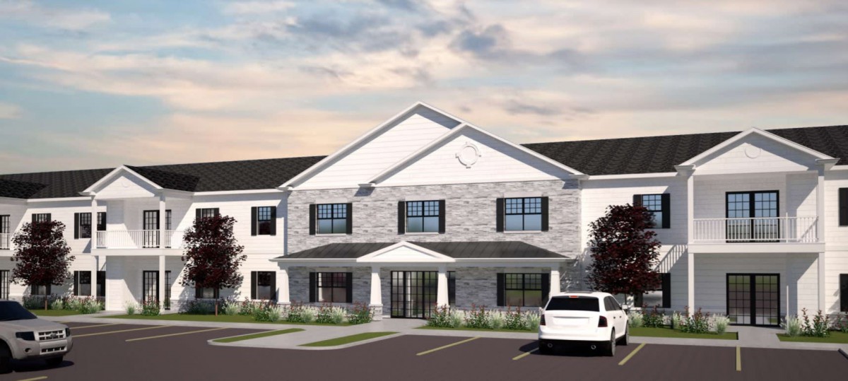 A suburban residential building with a parking lot in front, viewed during the day.