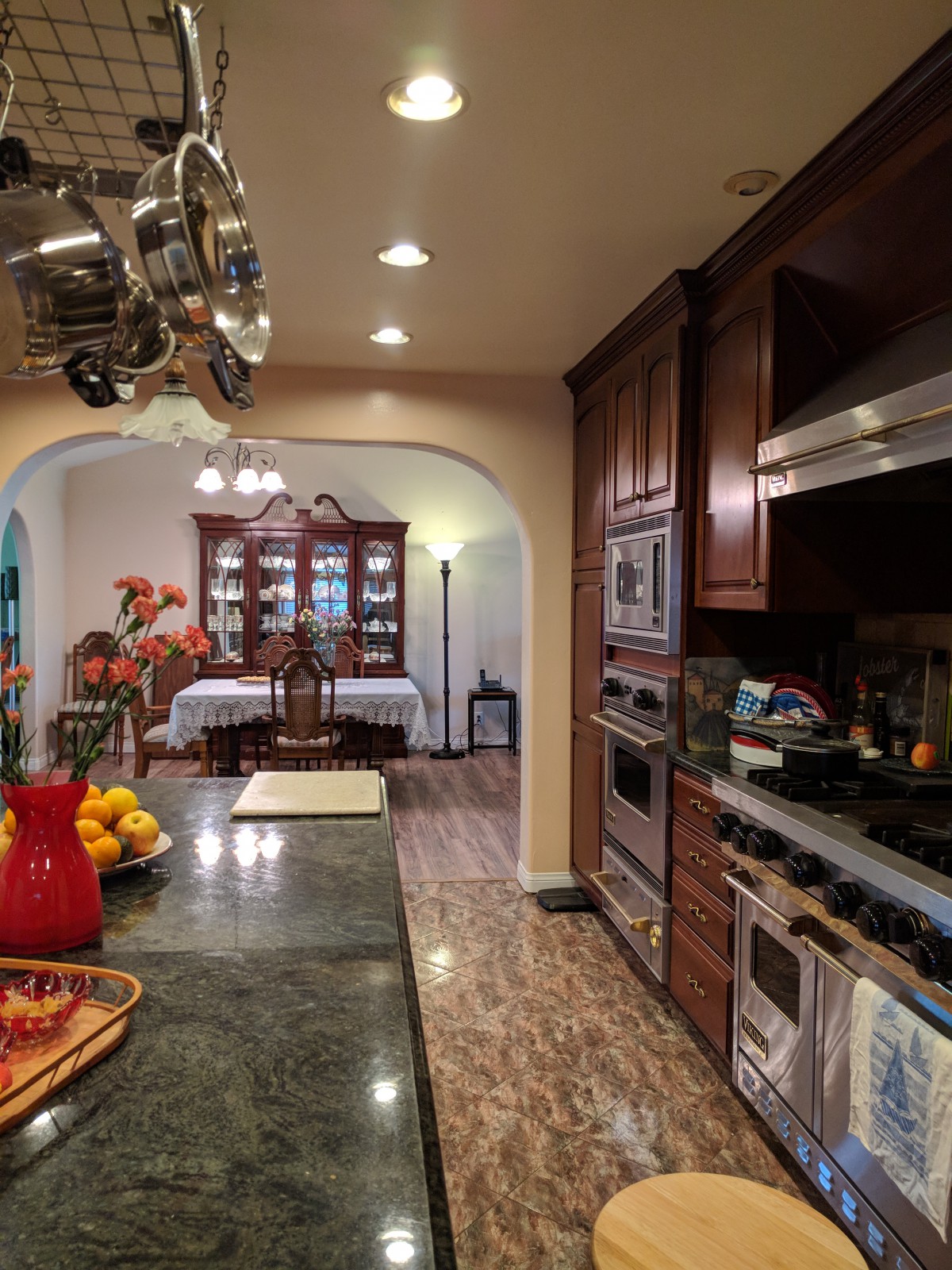 A traditional kitchen opens into a dining room, featuring wood cabinets and stainless steel appliances.