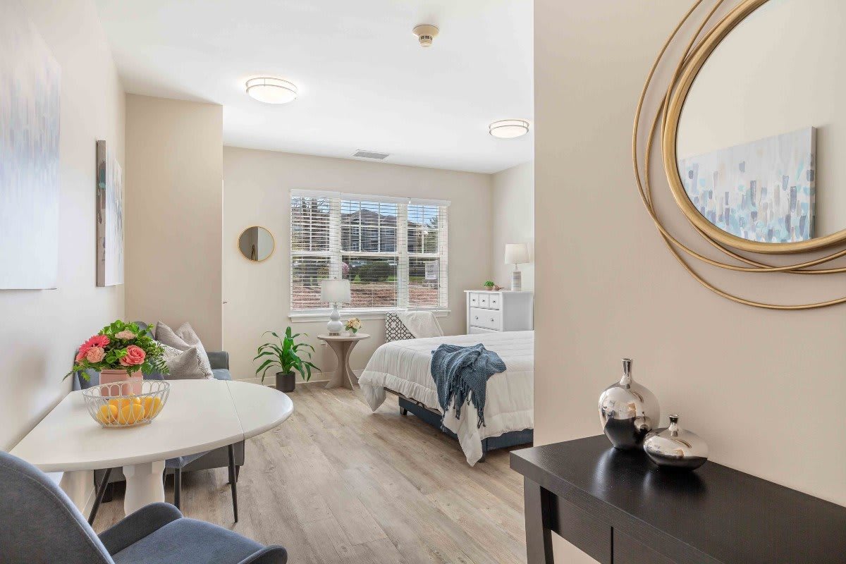A modern and bright bedroom with stylish decor, featuring a comfortable bed, plants, and ample natural light.