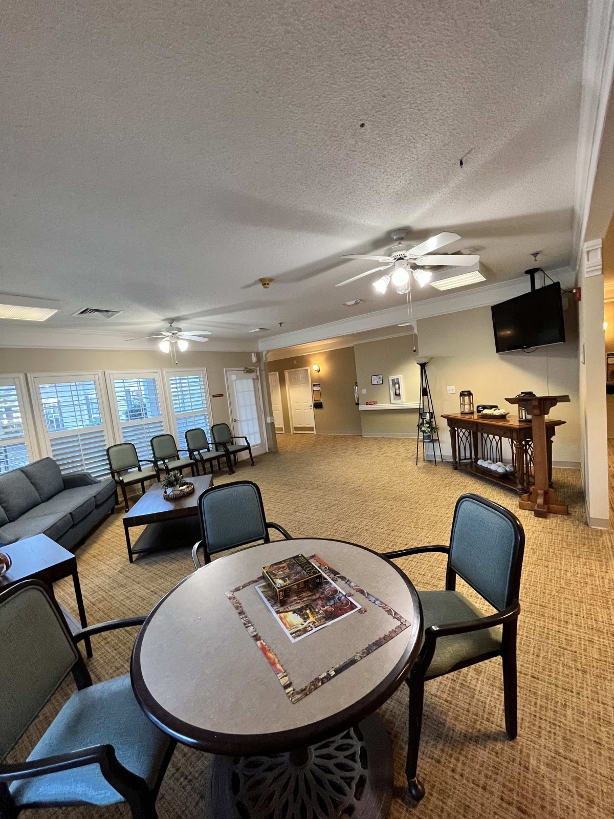 A spacious waiting room with seating, tables, and a television.