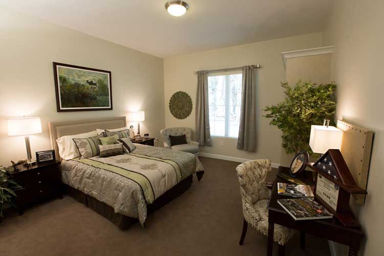 A cozy and well-decorated bedroom with a large bed, desk, lamp, and indoor plant enhancing the ambiance.