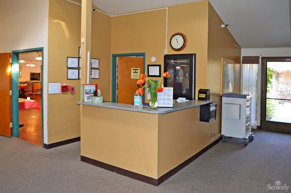 A tidy reception desk with a clock on the wall and flowers as decoration.