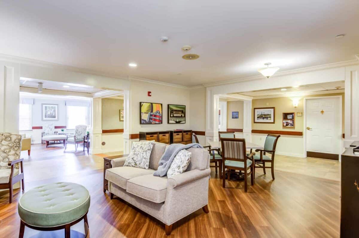 A cozy living room with a sofa, chairs, and artwork on the walls.