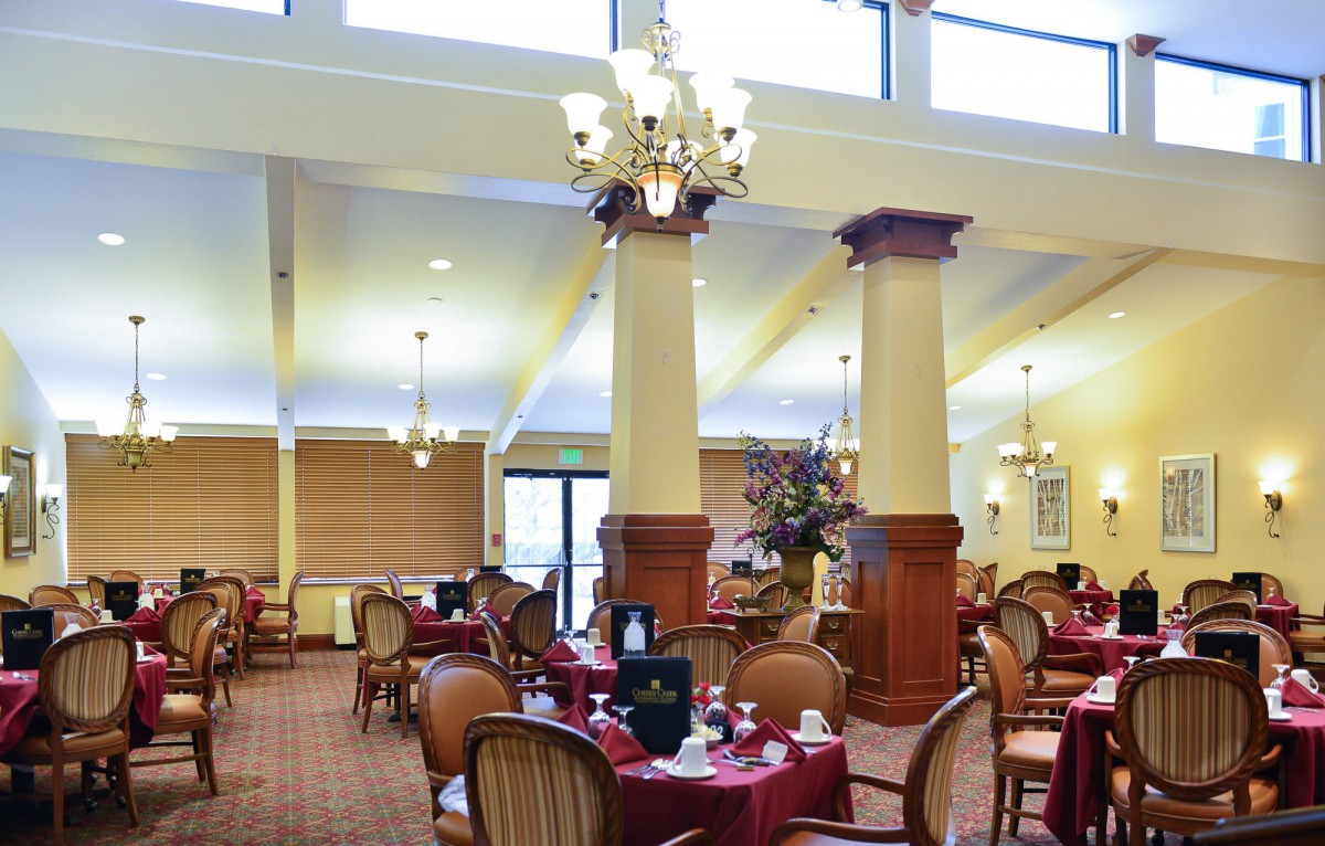An elegant dining room with arranged tables and chandeliers.